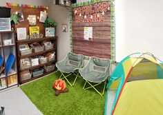 a room with two chairs and a tent in the grass next to bookshelves