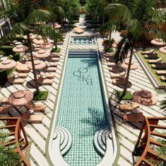 an outdoor swimming pool surrounded by lawn chairs and umbrellas with palm trees in the background