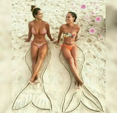 two women in bikinis sitting on the beach