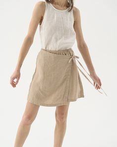 "Our take on a leisure tennis skirt - linen shorts with a wrap front, also known as a skort. The perfect blend of grace and comfort. Offered in medium-weight and exclusive linen. STYLE DETAILS * Regular fit * High rise * Elasticated waist * Wrap ties at the front * Mini length * Made from medium weight and exclusive linen SIZES & COLORS IN THE PICTURES * Model is wearing size M in Beige (medium) linen Model's height - 175 cm (5'9\"), bust 80 cm (31.5\"), waist 59 cm (23.2\"), hips 89 cm (35\"). Summer Cotton Skort With Built-in Shorts, Casual Tie Waist Mini Wrap Skirt, Summer Mini Length Relaxed Wrap Skirt, Linen Skirt For Vacation, Short Cotton Skirt For Summer, Cotton Mini Skort For Summer, Cotton Mini Skirt For Summer, Summer Skirt-style Shorts With Elastic Waistband, Summer Cotton Mini Skort