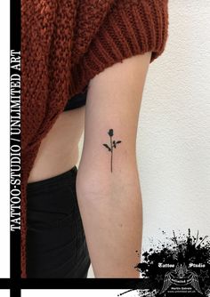 a small flower tattoo on the left side of the arm