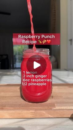 a jar filled with raspberry punch on top of a wooden table next to a sign