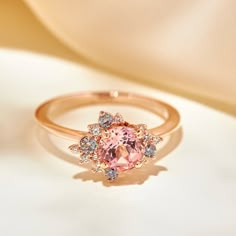 100% recycled precious metal Set in the center with a lovely approx. 1.25ct (6mm) round cut lab grown rosé sapphire. With a blush hue reminiscent of the color of morganite, our rosé sapphire features a slightly more saturated pink, and it offers a much better durability than morganite, making it ideal for an engagement ring! Available in two different tones: a hint of peach, or a hint of lilac One of a kind asymmetrical cluster halo featuring sparkly colorless lab grown diamonds, peppered with m Pink Diamond Gold Engagement Ring, Pink Sapphire Engagement Ring Vintage, Pink Sapphire Engagement Ring Rose Gold, Rose Themed Wedding, Pink Engagement Rings, Senior Ring, Rose Gold Morganite Engagement Ring, Pink Stone Engagement Rings, Pink Moissanite Ring