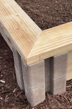 a bench made out of concrete blocks sitting in the ground next to mulchy grass