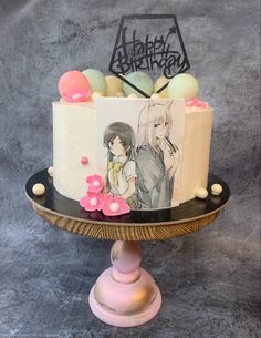 a birthday cake decorated with anime characters and flowers on a pedestal in front of a gray background