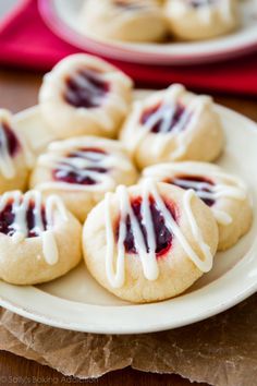 small cookies with white icing on a plate next to a red napkin and cup of coffee