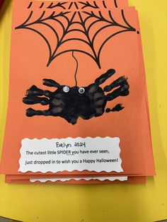 a handprinted spider on an orange card with the words happy halloween written below it