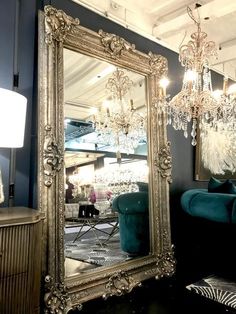 a large gold framed mirror sitting on top of a wooden table next to a blue couch