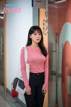 a woman standing in front of a glass door with her hand on her hip and looking at the camera