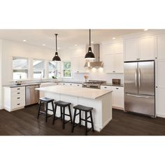 a kitchen with two stools and an island in front of the refrigerator freezer