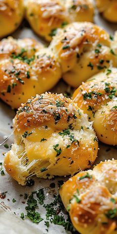 some bread rolls with cheese and herbs on them sitting on a white plate, ready to be eaten