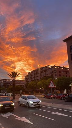 cars are driving down the street in front of some buildings at sunset or sunrise time