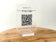 a clear acrylic sign with a qr code on it sitting on a wooden table