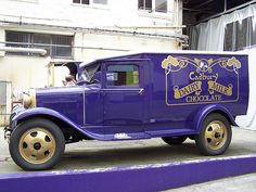 an old purple truck parked in front of a building