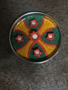 a cake in the shape of a cross on top of a table with red, yellow and green icing