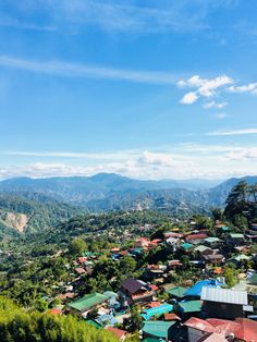 an aerial view of a small village in the mountains with blue skies and green trees