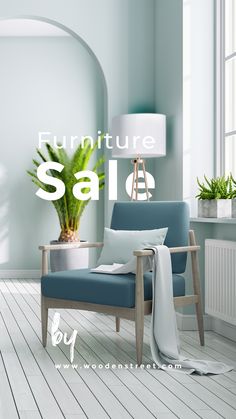 a blue chair sitting on top of a hard wood floor next to a lamp and potted plant