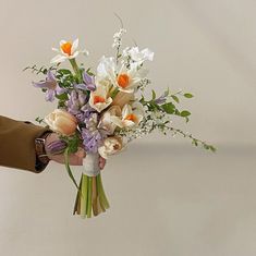 a person holding a bouquet of flowers in their left hand, with the other hand reaching for it