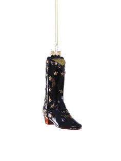 a pair of black cowboy boots hanging from a gold chain on a white background with an ornament in the shape of a boot