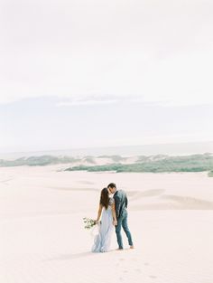 a bride and groom kissing in the desert