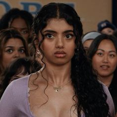 a woman with very large breast standing in front of a group of people wearing necklaces