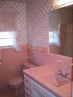 a bathroom with pink tile and white fixtures, including a sink, toilet, and window