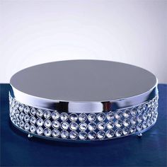 a round silver tray with lots of crystal stones on the bottom and sides, sitting on a blue surface