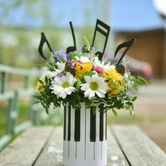 an arrangement of flowers in a white vase on a wooden table with black and white stripes