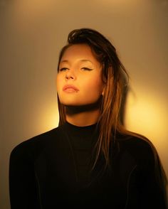 a woman with her eyes closed standing in front of a wall