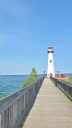 a light house sitting on top of a wooden pier next to the ocean and blue sky