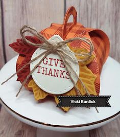 a white plate topped with an orange and yellow thanksgiving treat bag next to a wooden wall