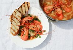 there is a white plate with some food on it and a bowl of soup in the background