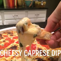 a hand holding a piece of cheese pizza with the words cheesy caprese dip on it