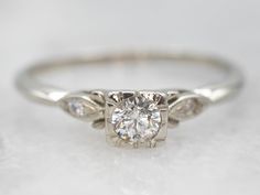 a white gold engagement ring with three diamonds on the band and a center diamond in the middle