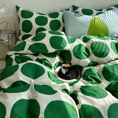 a bed with green and white polka dots on the comforter, pillows and pillow cases