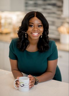 a woman sitting at a table holding a coffee mug