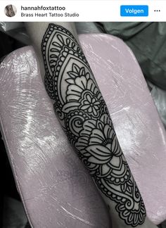 an arm with a black and white tattoo design on the left side of its arm