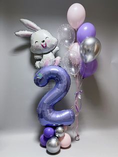 the number two balloon is decorated with balloons and an easter bunny sitting on top of it