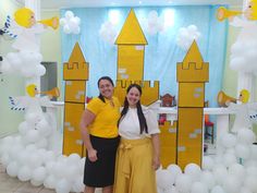 two women standing next to each other in front of a backdrop with castle and balloons