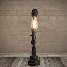 an old fashioned lamp with a light bulb on it's end sitting in front of a brick wall