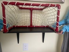 a person holding a soccer goal in front of a wall mounted shelf with two balls on it