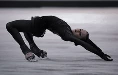 a woman in black is doing a trick on the skateboard with her hands behind her head