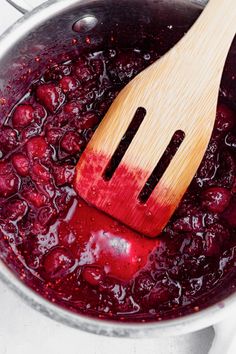 a wooden spatula in a pot filled with cranberry sauce