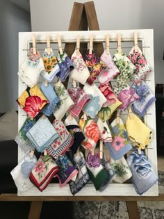 an easel with many small handkerchiefs hanging on clothes pins