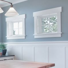 a kitchen with blue walls and white trim on the windows, along with a wooden table