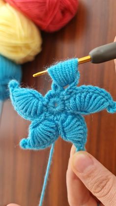 someone crocheting a snowflake ornament with yarn on a table