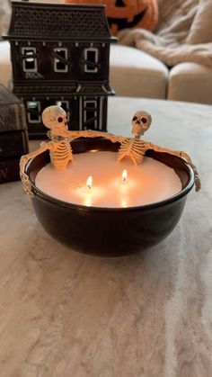 two skeleton candles in a bowl on a table