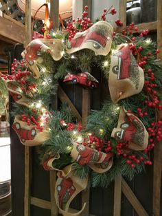 a christmas wreath is hanging on the side of a wooden door with lights and decorations