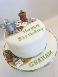 a birthday cake with gardening related items on the top, and happy birthday graham written in green