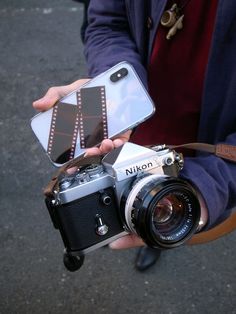 a person holding up a camera and cell phone